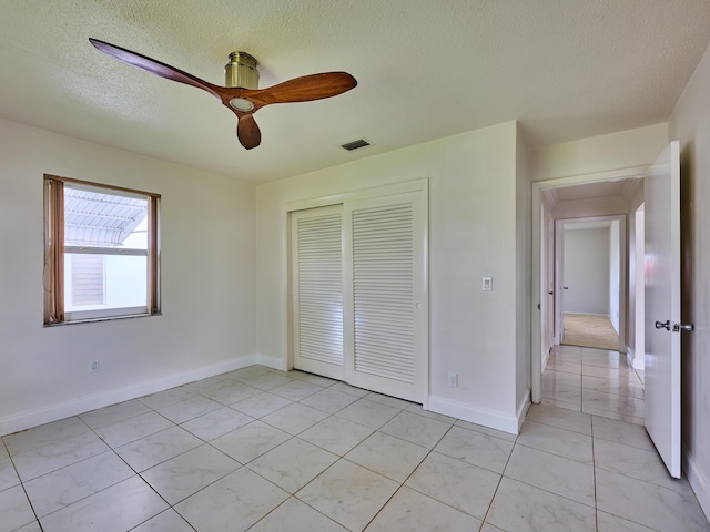 unfurnished bedroom featuring light tile patterned flooring, a textured ceiling, baseboards, visible vents, and a closet