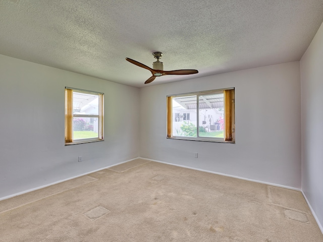 empty room with light colored carpet, ceiling fan, and a healthy amount of sunlight