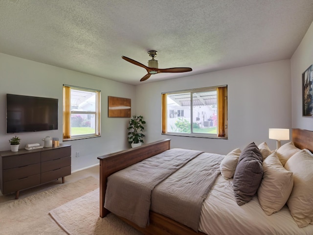 bedroom featuring ceiling fan, light carpet, and a textured ceiling