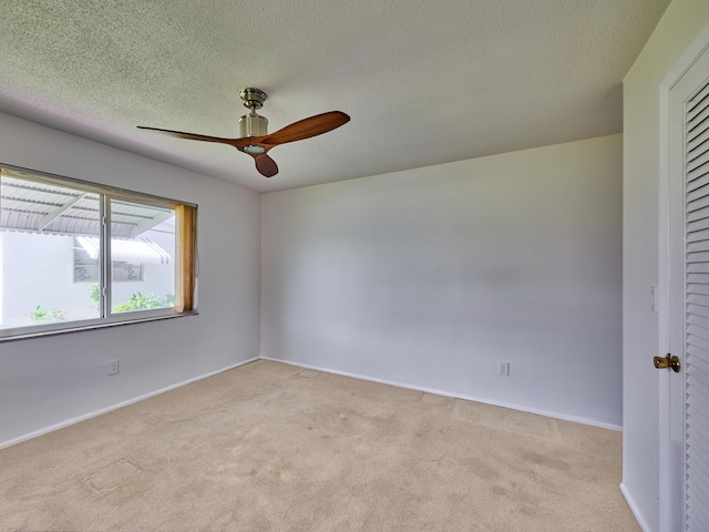 unfurnished room with a ceiling fan, a textured ceiling, light carpet, and baseboards