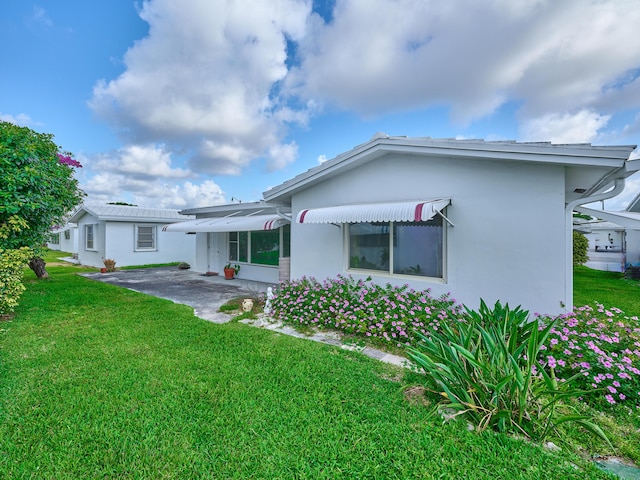 rear view of property featuring stucco siding and a yard