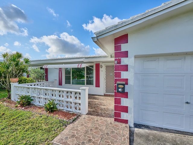 doorway to property featuring covered porch, an attached garage, and stucco siding