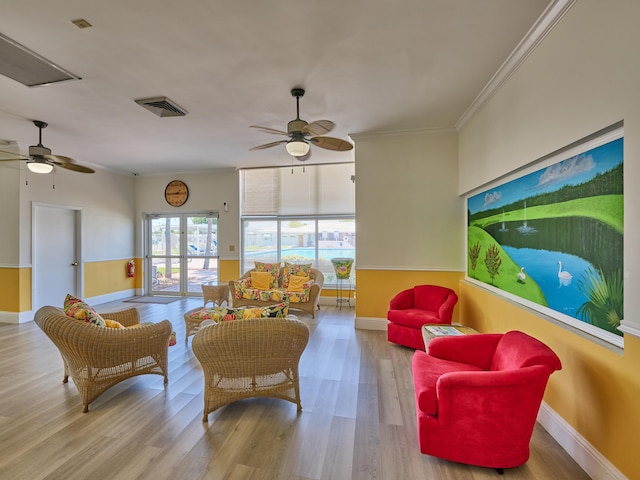living area with a ceiling fan, visible vents, and wood finished floors