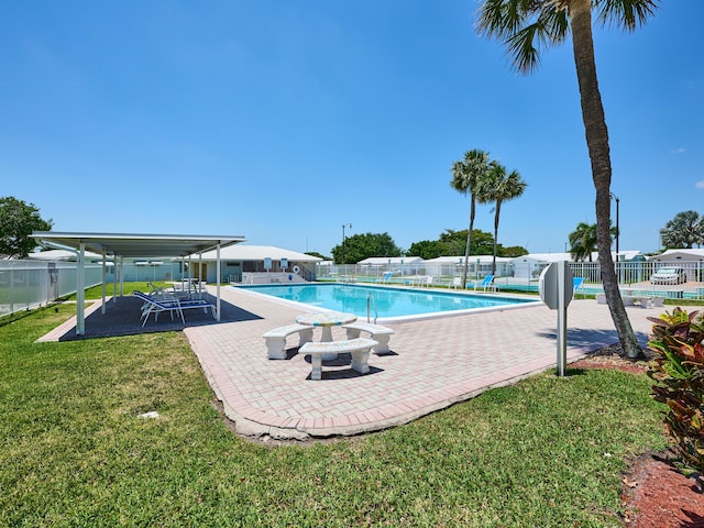 pool with a lawn, a patio area, and fence