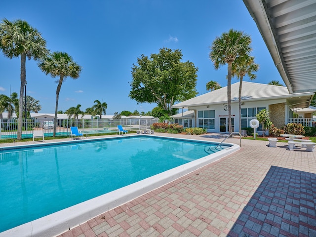 community pool with fence and a patio area