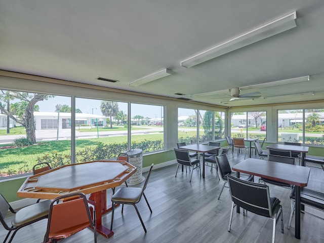 sunroom / solarium with baseboards, a wealth of natural light, wood finished floors, and visible vents
