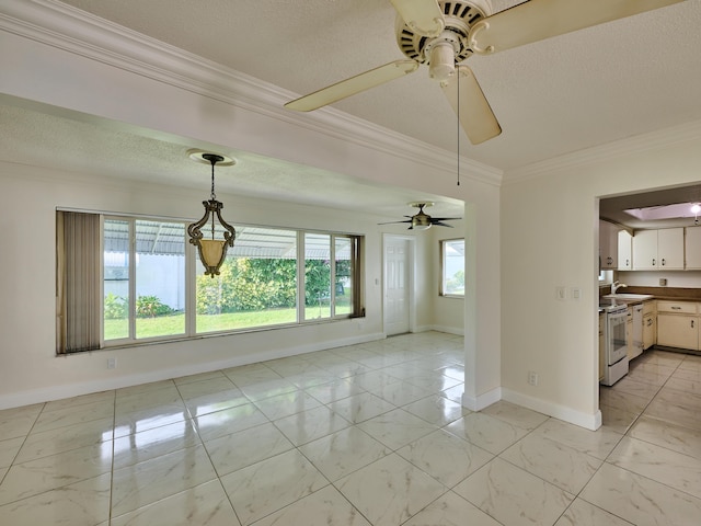 empty room featuring baseboards, a ceiling fan, a textured ceiling, and crown molding