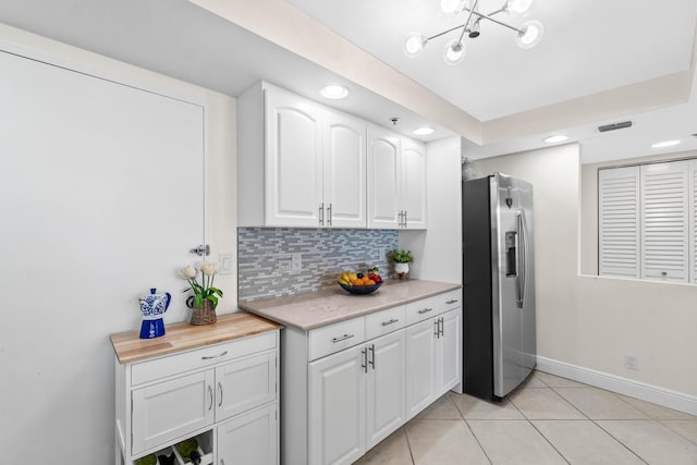 kitchen with stainless steel fridge, white cabinets, light countertops, tasteful backsplash, and recessed lighting