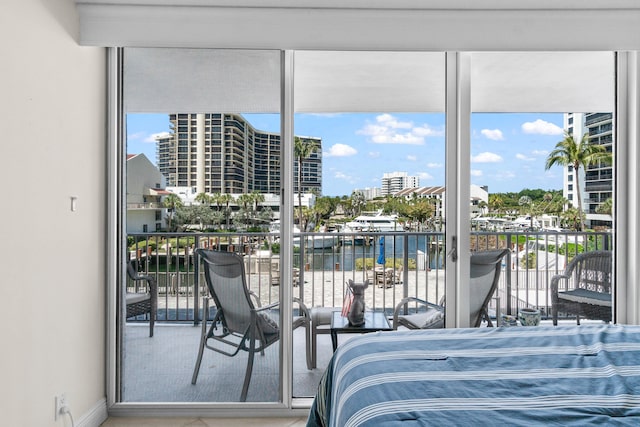bedroom with a city view, expansive windows, a water view, and access to exterior