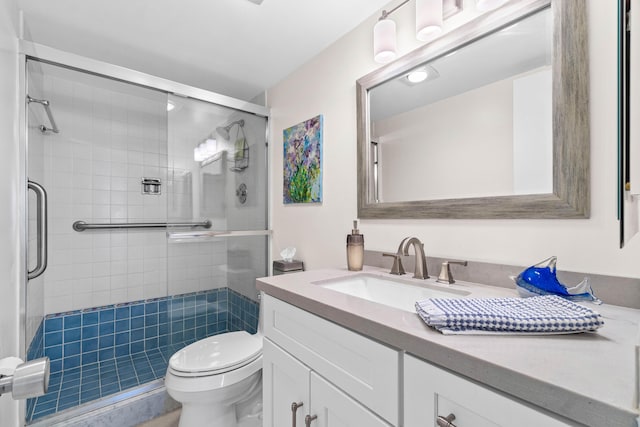 bathroom featuring toilet, a shower stall, and vanity
