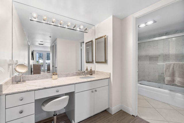 bathroom with enclosed tub / shower combo, baseboards, visible vents, vanity, and wood finished floors