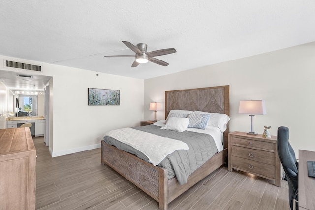 bedroom featuring baseboards, ensuite bathroom, ceiling fan, visible vents, and light wood-style floors