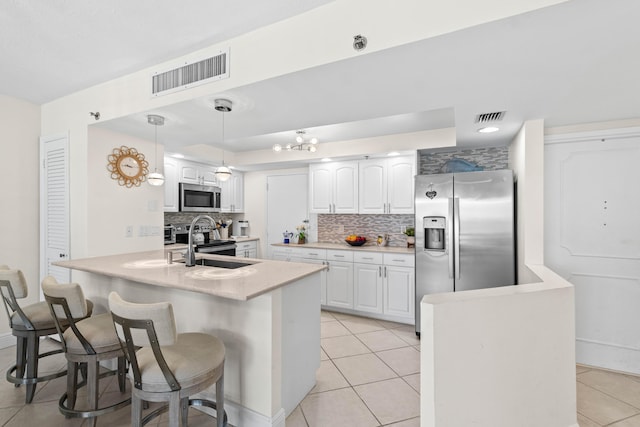 kitchen featuring a peninsula, light tile patterned floors, stainless steel appliances, visible vents, and tasteful backsplash