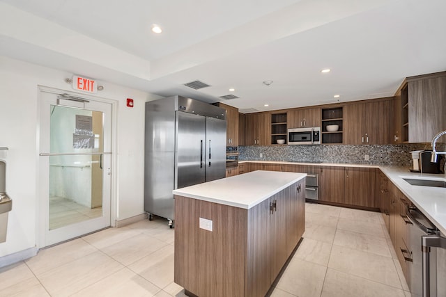kitchen with a sink, open shelves, visible vents, appliances with stainless steel finishes, and decorative backsplash