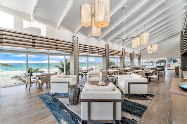 living area with a water view, a wealth of natural light, high vaulted ceiling, and beam ceiling