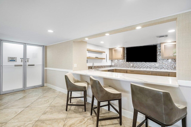 kitchen featuring baseboards, a breakfast bar, a peninsula, and visible vents