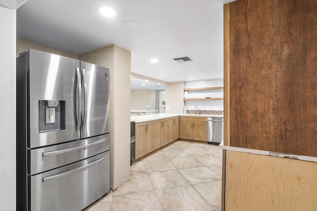 kitchen with light brown cabinetry, stainless steel appliances, visible vents, a sink, and light countertops