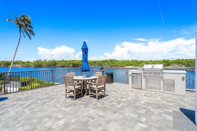 view of patio / terrace featuring area for grilling, outdoor dining area, a water view, and an outdoor kitchen