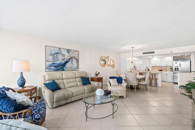 living area with light tile patterned floors, an inviting chandelier, and visible vents