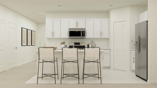 kitchen featuring appliances with stainless steel finishes, a kitchen bar, white cabinetry, and a center island