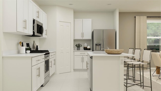 kitchen with appliances with stainless steel finishes, light tile patterned flooring, a kitchen island with sink, and a kitchen breakfast bar