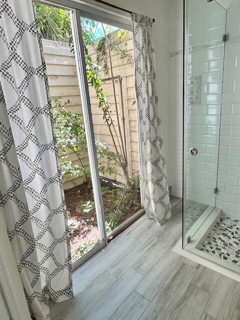 full bath with wood finished floors, a healthy amount of sunlight, and a shower stall