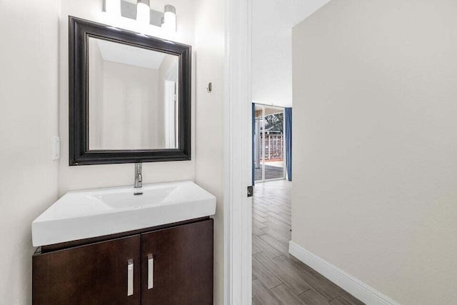 bathroom with wood finished floors, vanity, and baseboards