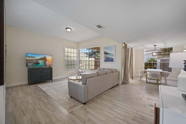 living area with visible vents, light wood-style flooring, and baseboards