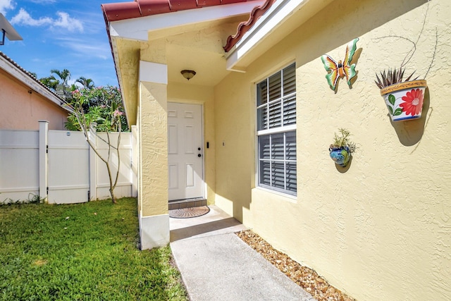 8024 Stirrup Cay Ct, Boynton Beach, FL 33436 - view of exterior entry featuring stucco siding, a yard, and fence