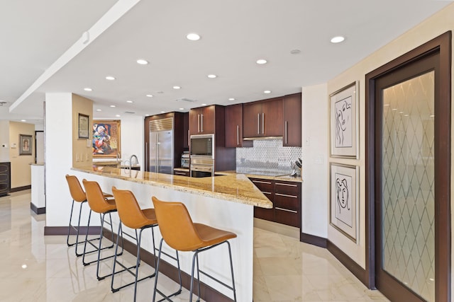 300 SE 5th Ave Unit 2050, Boca Raton, FL 33432 - kitchen featuring baseboards, marble finish floor, a kitchen bar, a peninsula, and built in refrigerator