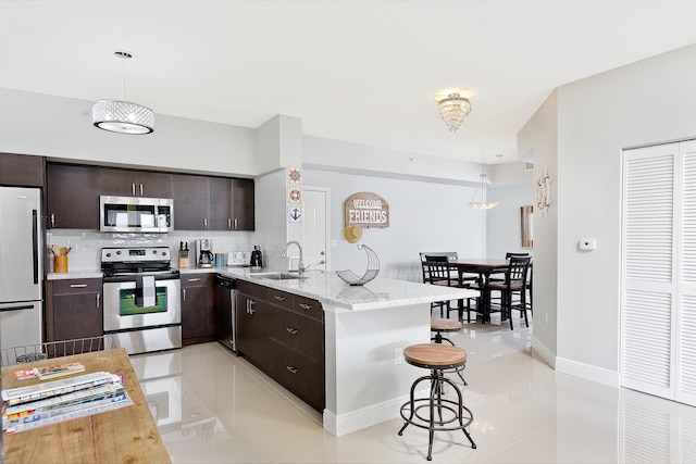 255 NE 3rd Ave Unit 2501, Delray Beach, FL 33444 - kitchen with light tile patterned floors, stainless steel appliances, dark brown cabinets, a sink, and a peninsula