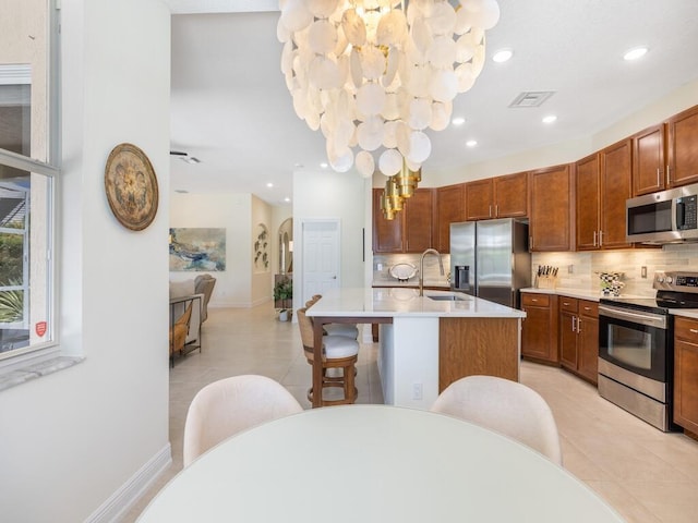 6000 Venetto Way, Vero Beach, FL 32967 - kitchen featuring light tile patterned floors, decorative backsplash, appliances with stainless steel finishes, light countertops, and a center island with sink