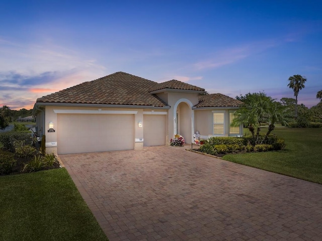 6000 Venetto Way, Vero Beach, FL 32967 - mediterranean / spanish home featuring a tiled roof, decorative driveway, stucco siding, a yard, and a garage