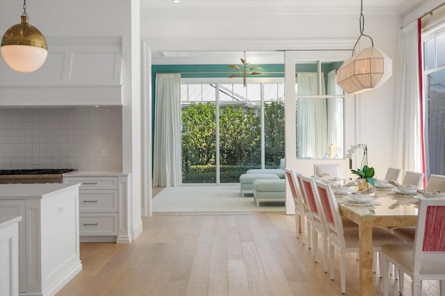 dining space featuring light wood-style floors and crown molding