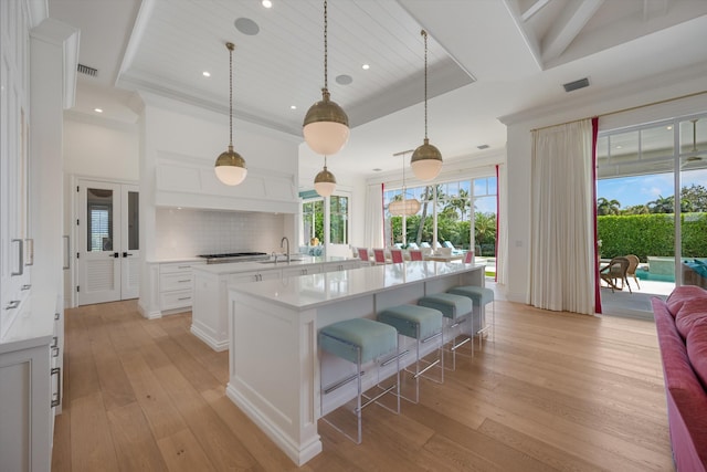 kitchen with light wood-type flooring, light countertops, stainless steel gas cooktop, and a spacious island