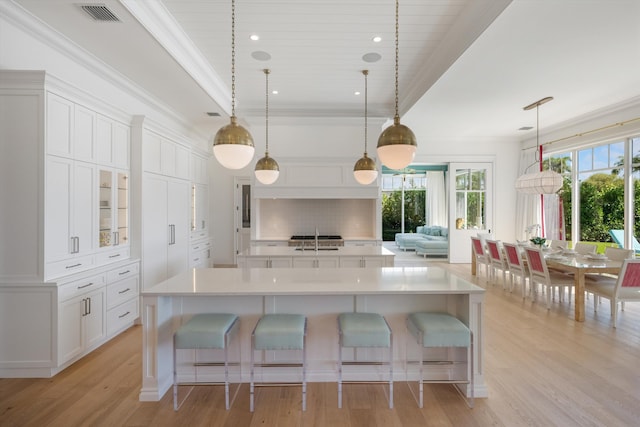 kitchen featuring visible vents, a large island, a healthy amount of sunlight, and ornamental molding