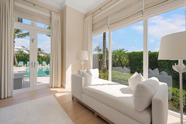 living area featuring crown molding, light wood-style flooring, and a wealth of natural light