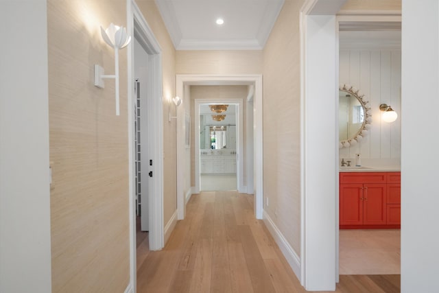 hallway with crown molding, recessed lighting, a sink, and light wood-style floors