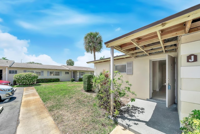 exterior space with stucco siding and a front lawn