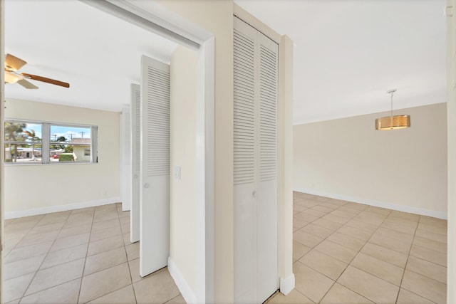 hall featuring light tile patterned flooring and baseboards