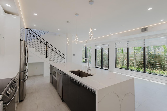 kitchen featuring visible vents, modern cabinets, dark cabinetry, a sink, and appliances with stainless steel finishes