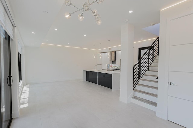 kitchen with a kitchen island, modern cabinets, light countertops, wall chimney exhaust hood, and a notable chandelier