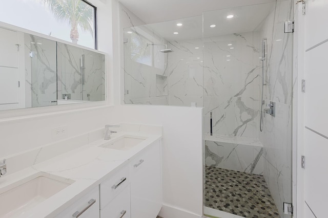 bathroom with recessed lighting, a sink, a marble finish shower, and double vanity
