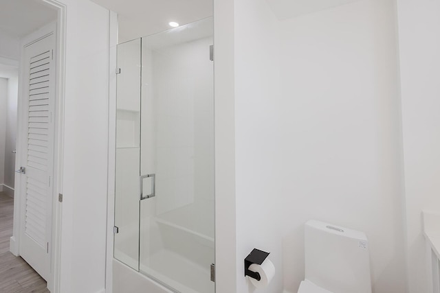 full bathroom with toilet, a shower with door, recessed lighting, and wood finished floors