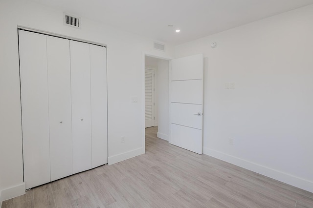 unfurnished bedroom with baseboards, light wood finished floors, and visible vents