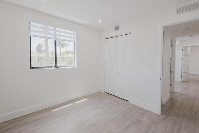 unfurnished bedroom with baseboards, visible vents, light wood-style flooring, and a closet