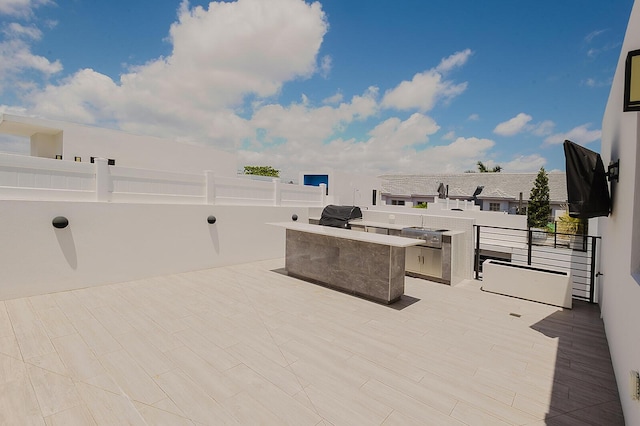view of patio with outdoor wet bar, fence, and area for grilling