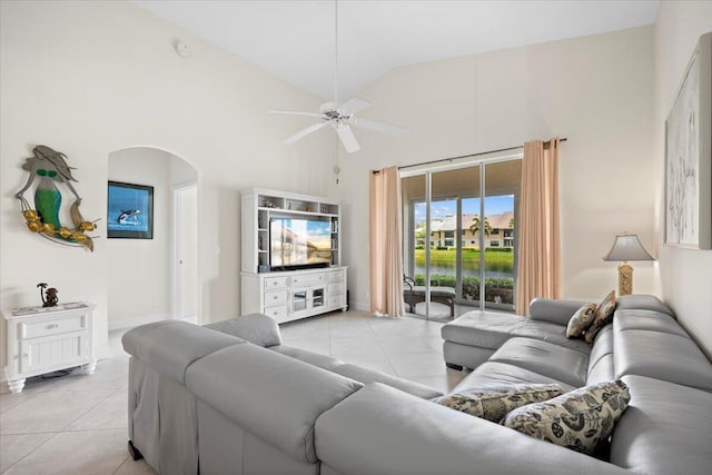 living area with ceiling fan, arched walkways, baseboards, high vaulted ceiling, and light tile patterned flooring