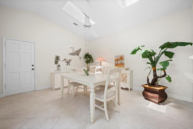 dining room with baseboards, ceiling fan, light tile patterned floors, and vaulted ceiling with skylight