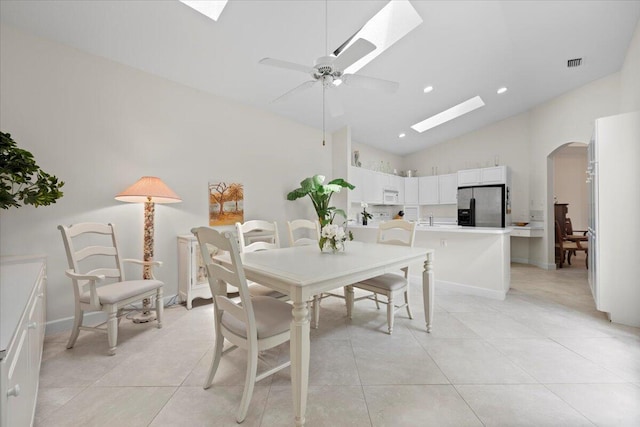 dining space with ceiling fan, visible vents, a skylight, arched walkways, and light tile patterned floors